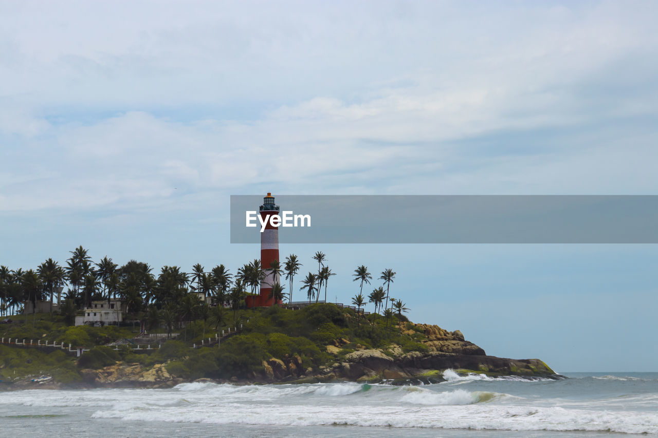 Lighthouse by sea against sky