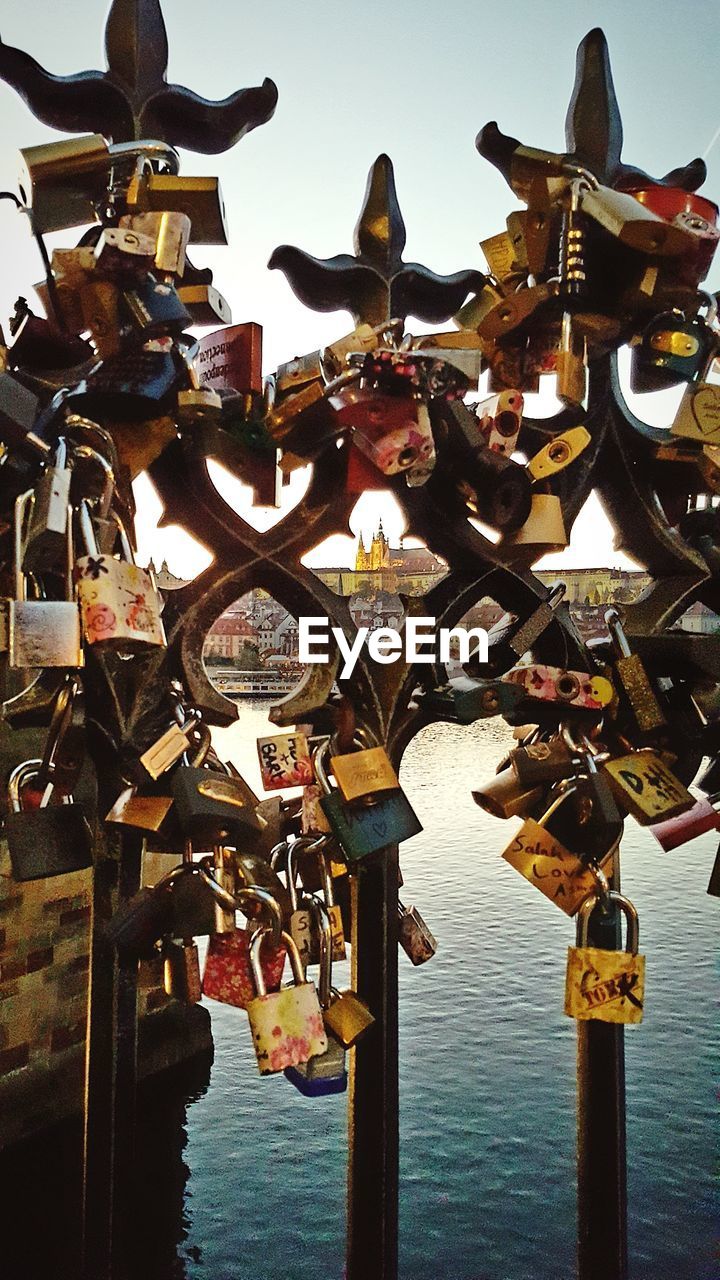 CLOSE-UP OF LOVE PADLOCKS HANGING ON RIVER AGAINST SKY