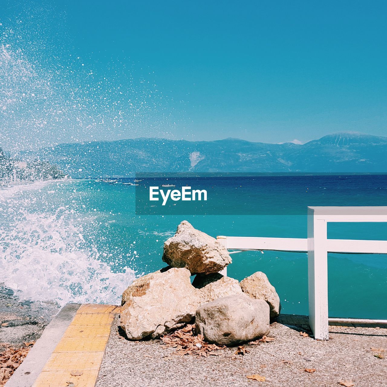 Sea waves splashing against clear blue sky