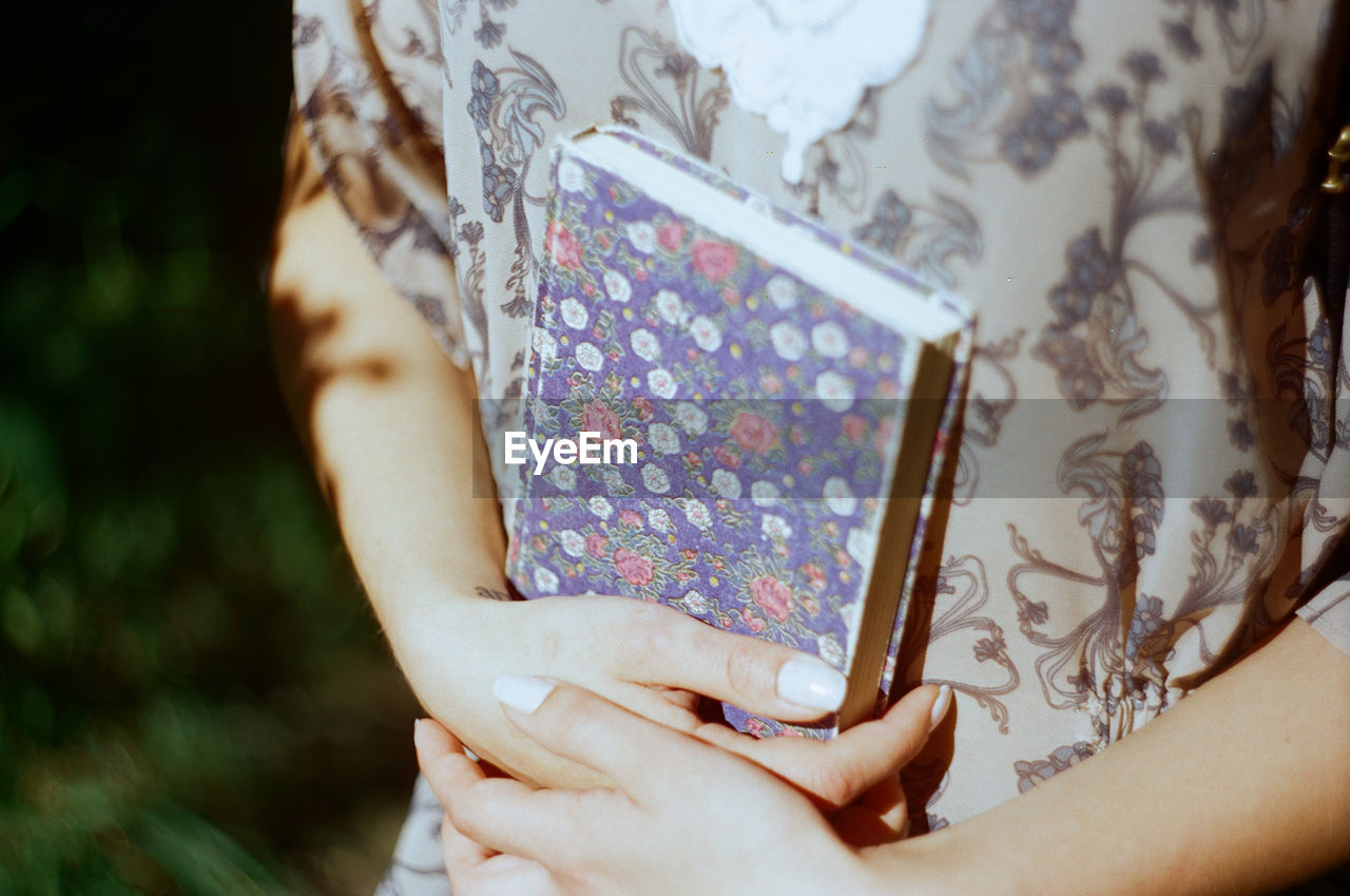 Midsection of woman holding floral pattern book