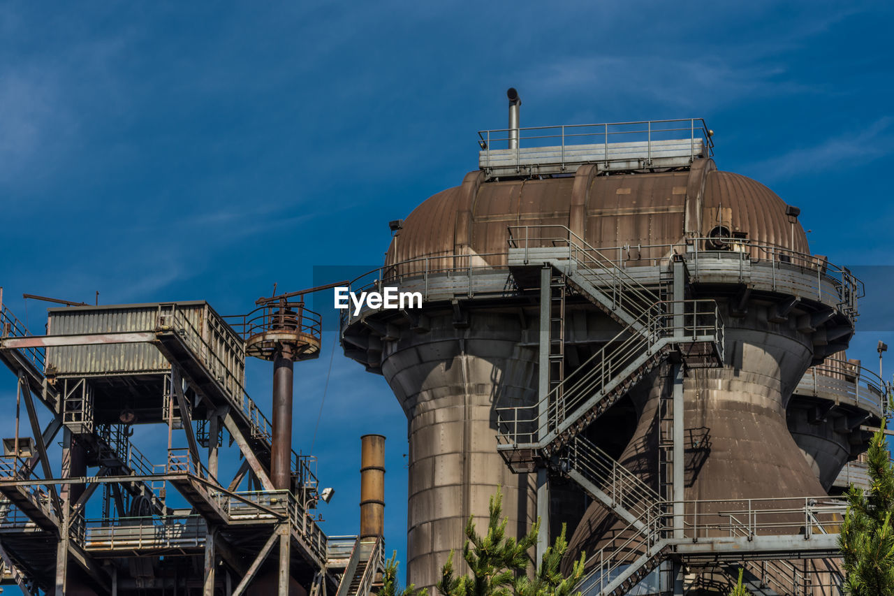 Low angle view of factory against blue sky