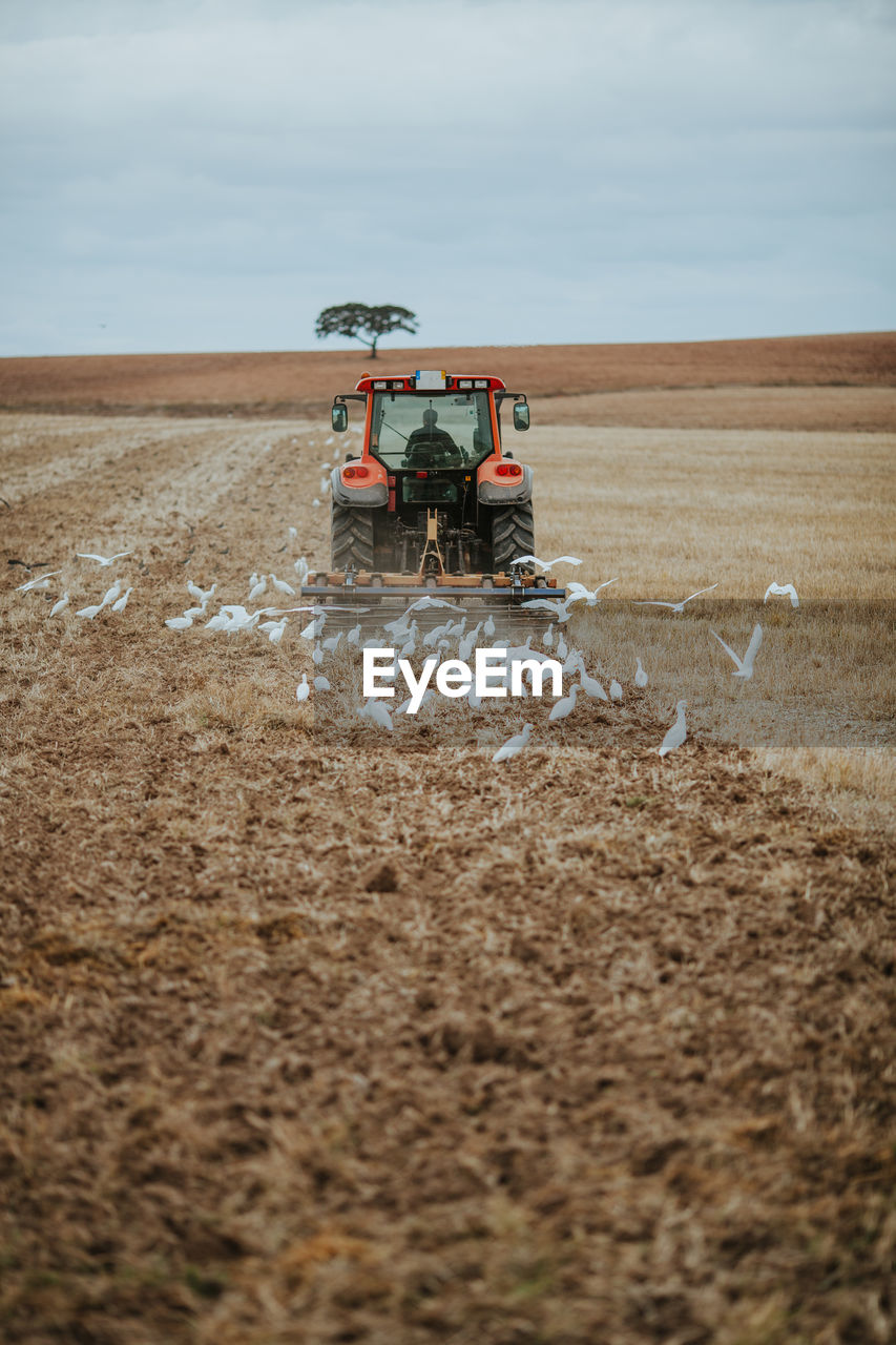 Tractor on agricultural field against sky