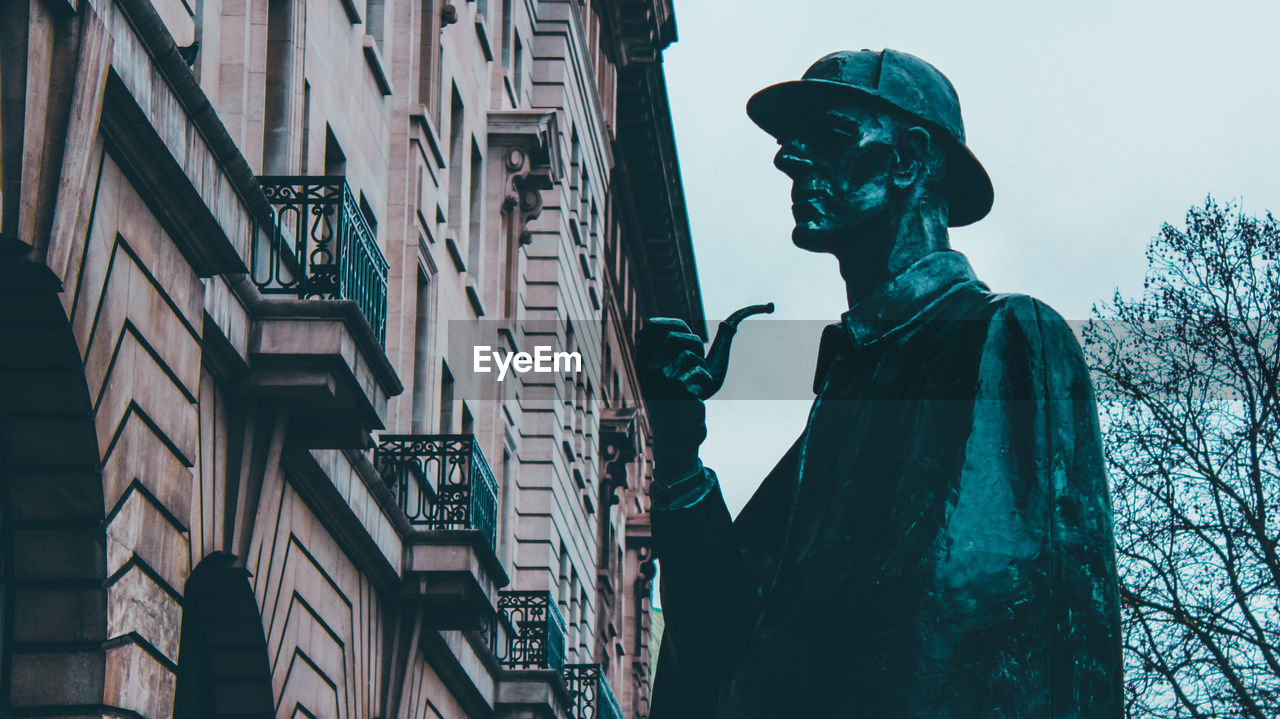 Low angle view of sherlock statue against buildings in the city of london