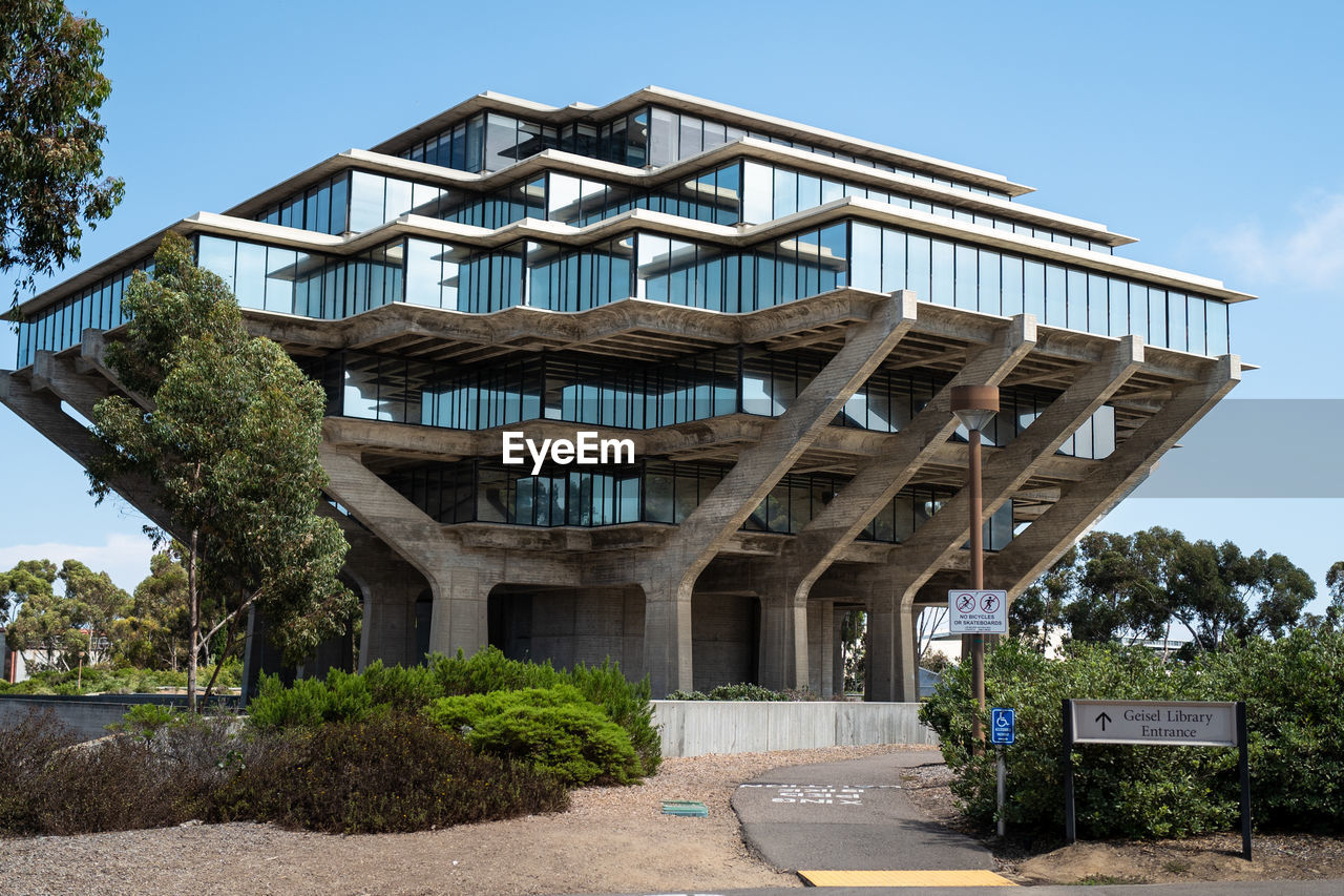 LOW ANGLE VIEW OF BUILDING BY TREES AGAINST SKY