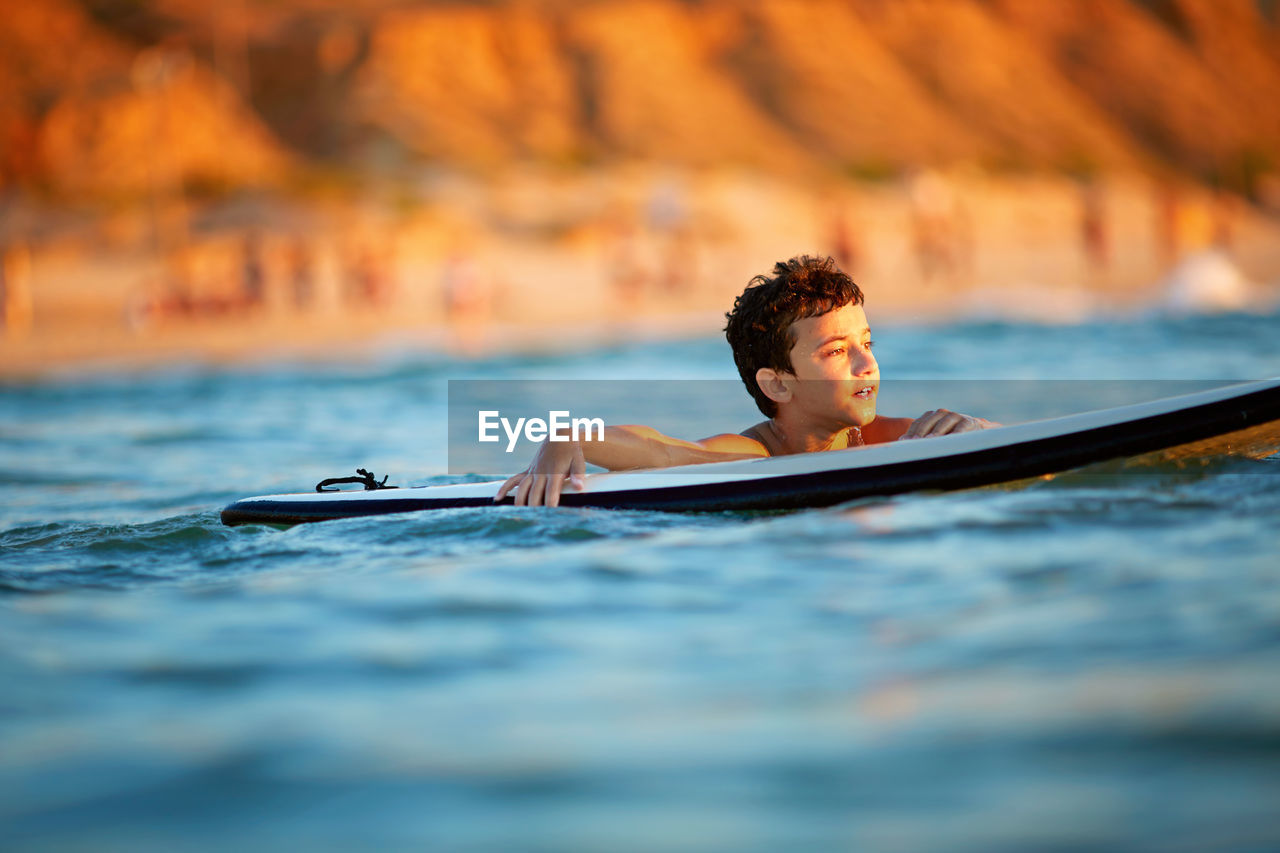 Young surfer, happy young boy in the ocean on surfboard