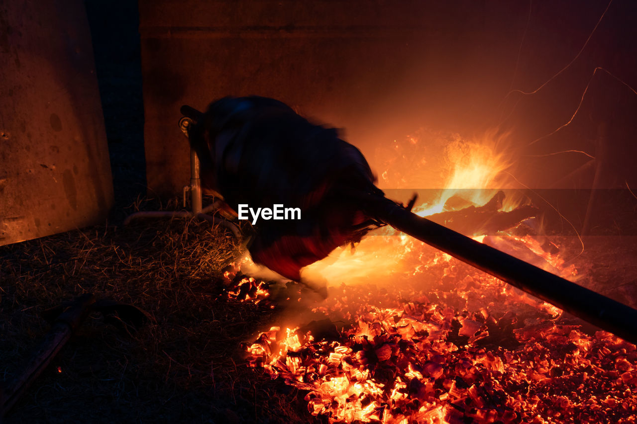 Silhouette of whole pig spinning on a spit