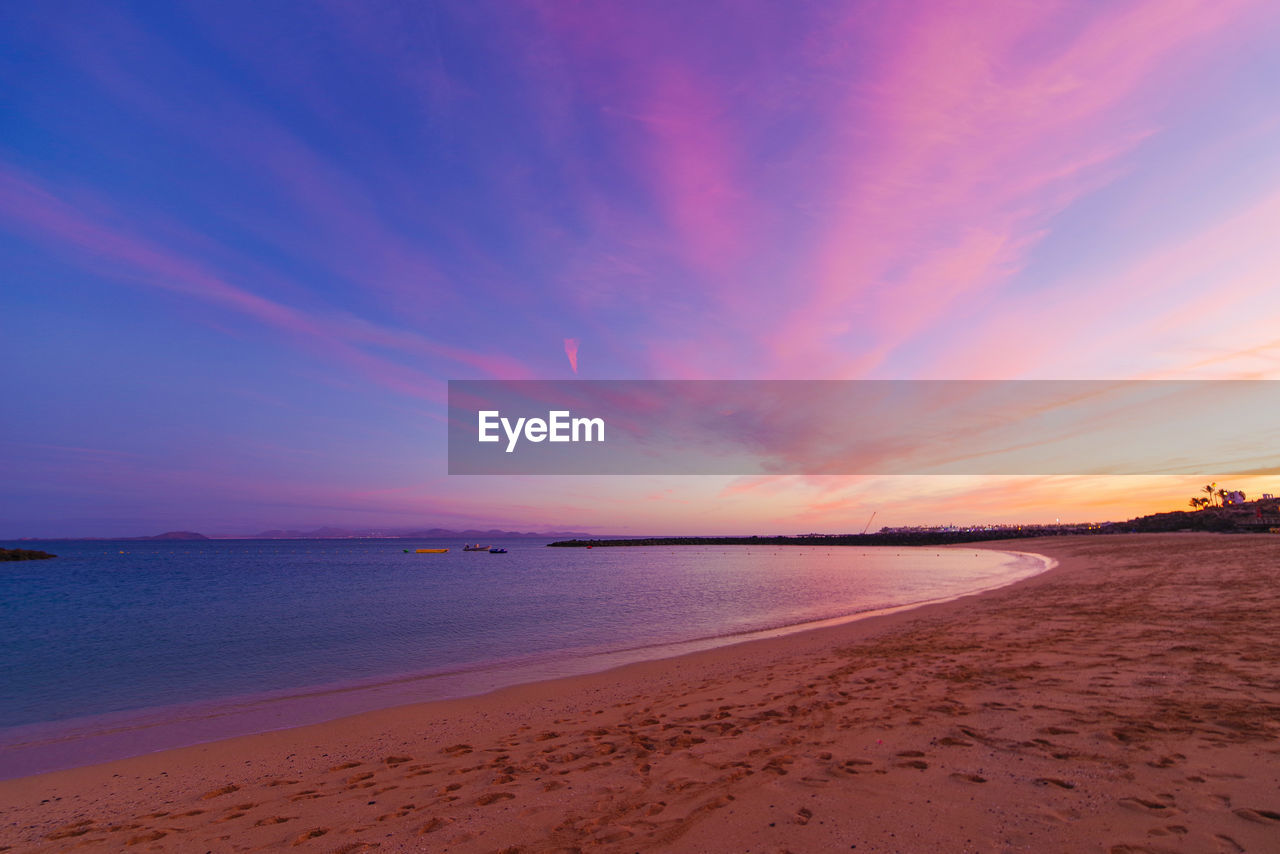 SCENIC VIEW OF BEACH AGAINST SKY AT SUNSET
