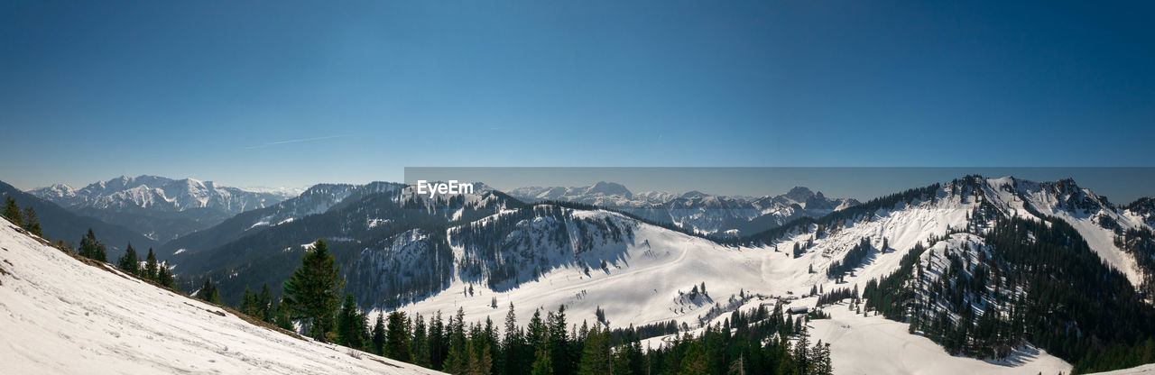 Panoramic view of snowcapped mountains against blue sky