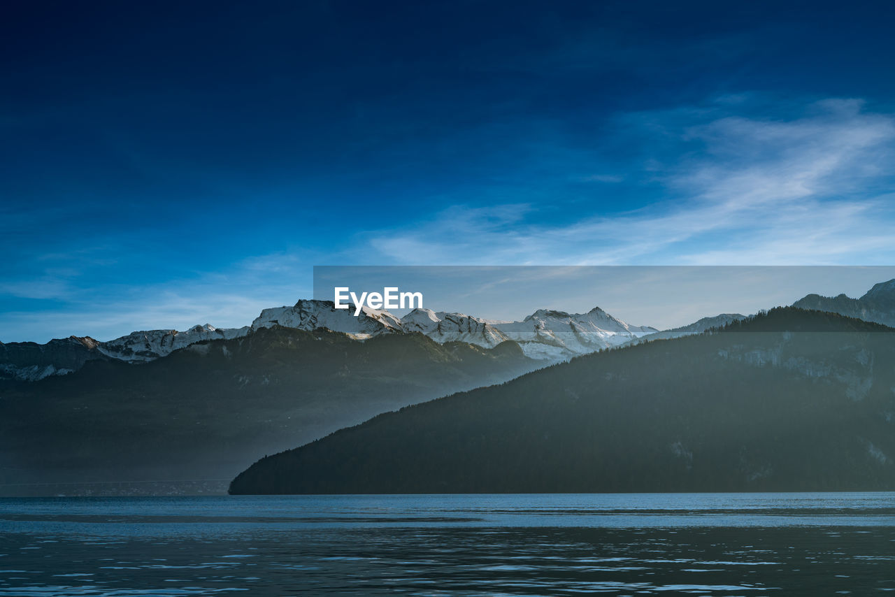 Scenic view of sea and mountains against blue sky