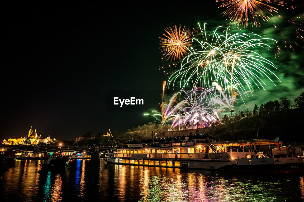 LOW ANGLE VIEW OF FIREWORK DISPLAY OVER RIVER AGAINST SKY