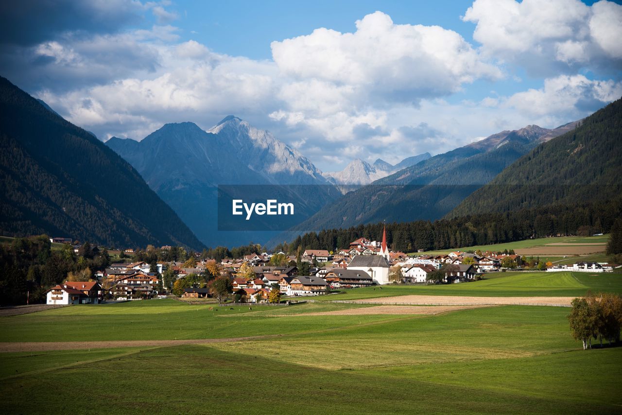 Houses on field by mountains against sky