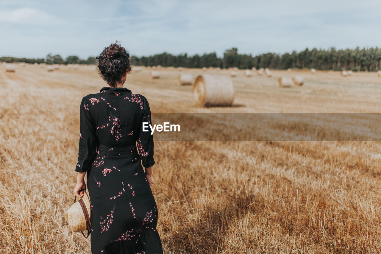 Rear view of woman standing in farm against sky