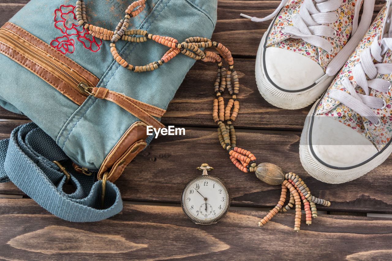 Close-up of shoes with pocket watch and handbag on table