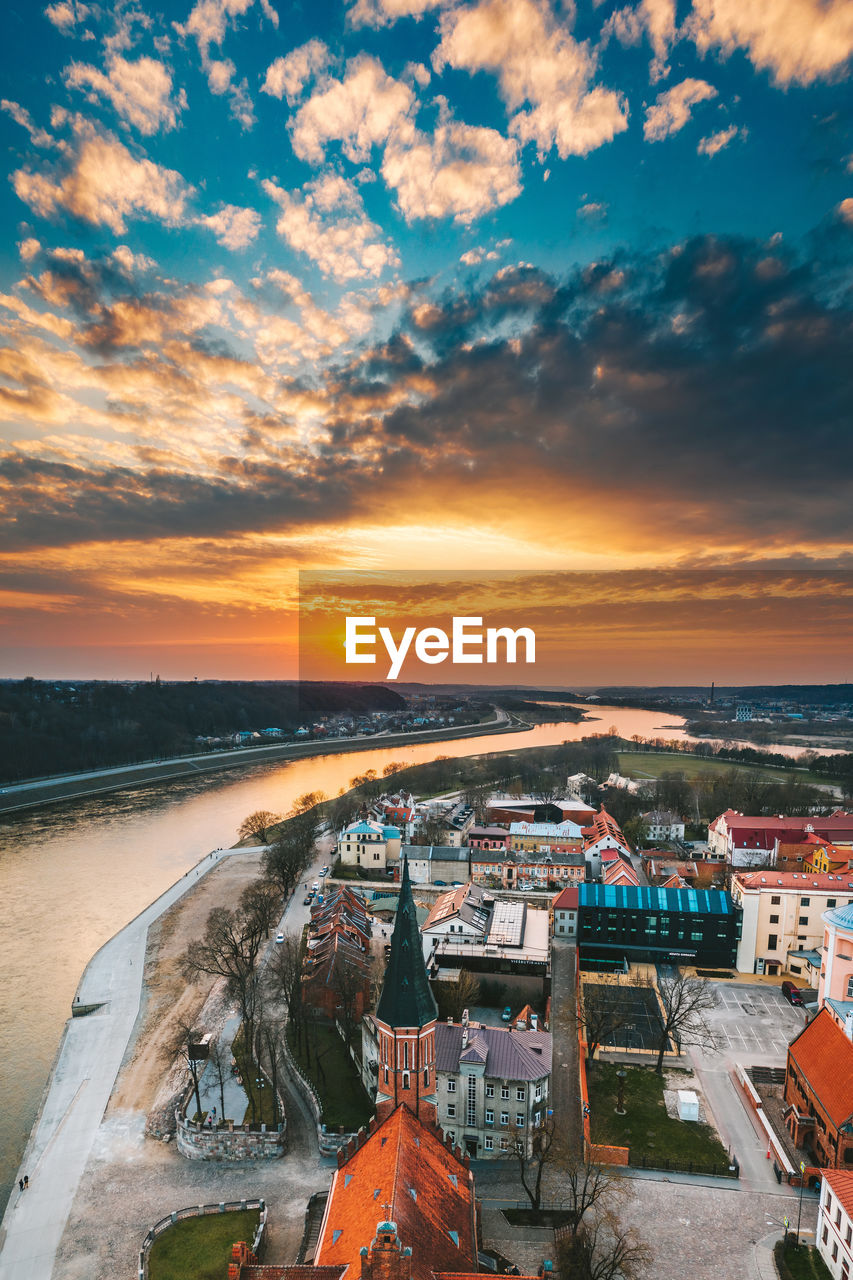 HIGH ANGLE VIEW OF BUILDINGS IN CITY AGAINST SKY DURING SUNSET