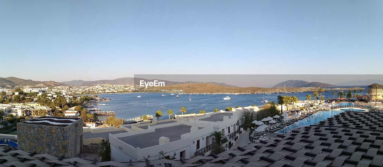 HIGH ANGLE VIEW OF TOWNSCAPE AND SEA AGAINST CLEAR SKY