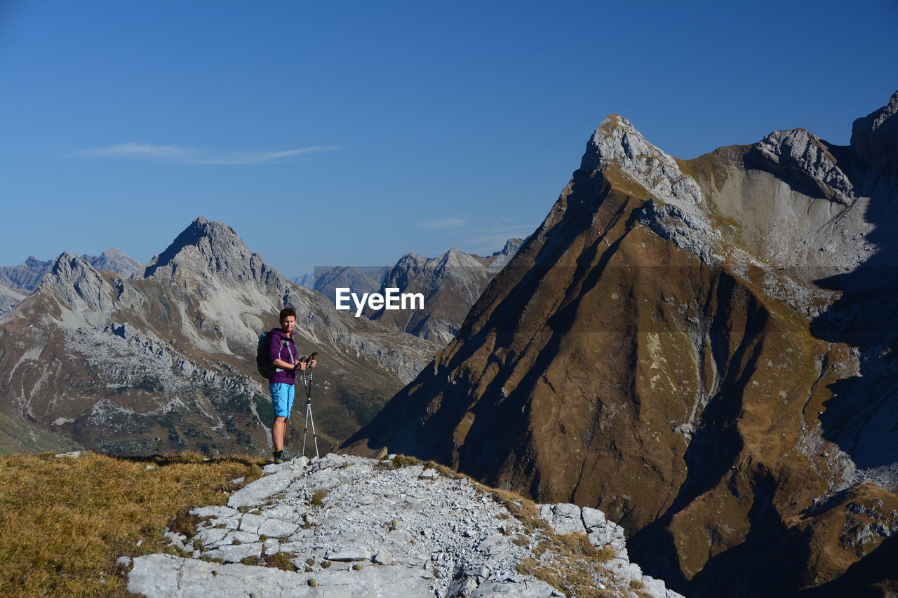 Man standing on rocks by mountain against sky