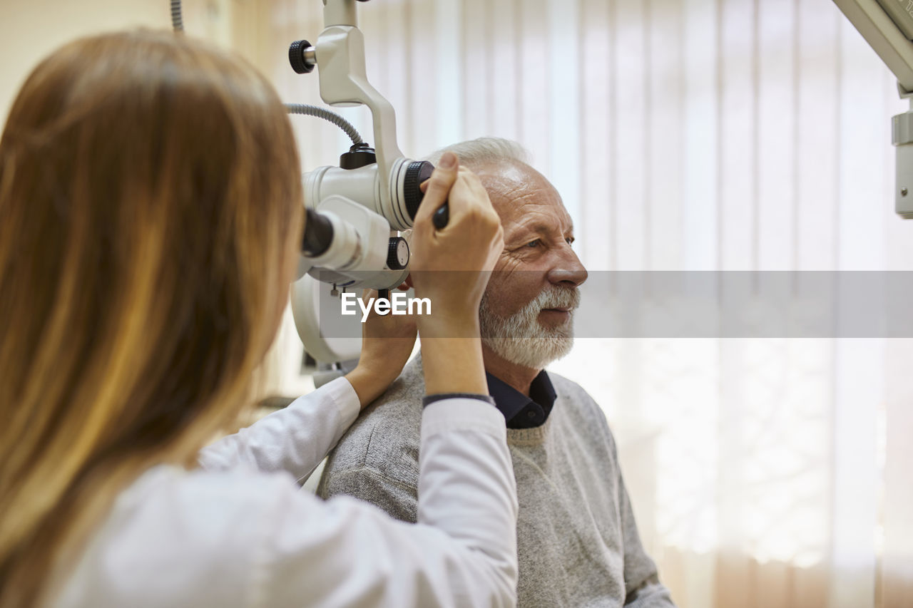 Ent physician examining ear of a senior man