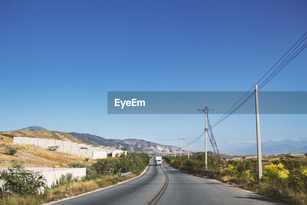 Road by mountain against clear blue sky