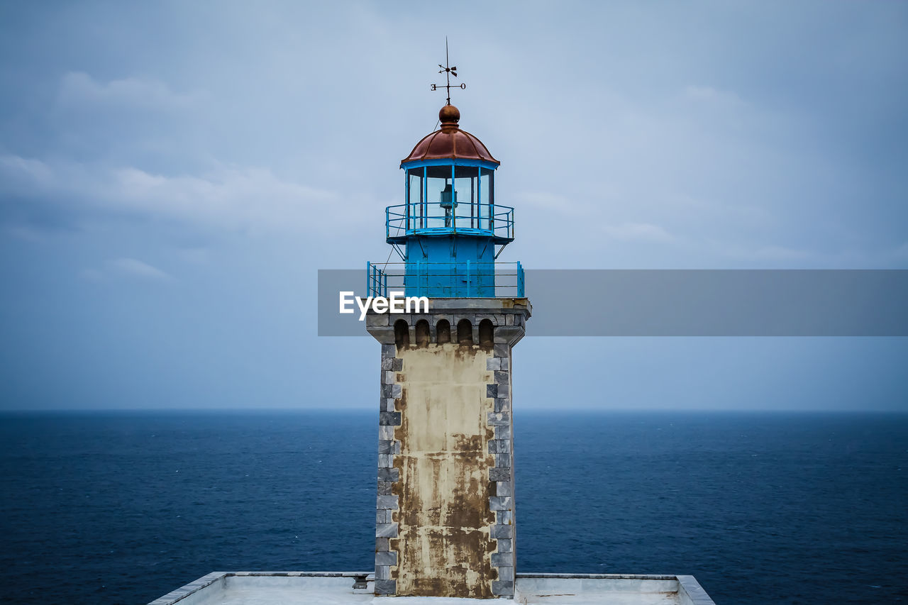 LIGHTHOUSE BY SEA AGAINST SKY AT BUILDING