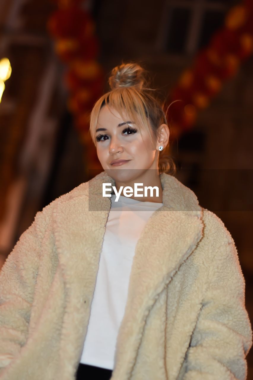 Portrait of young woman standing outdoors at night