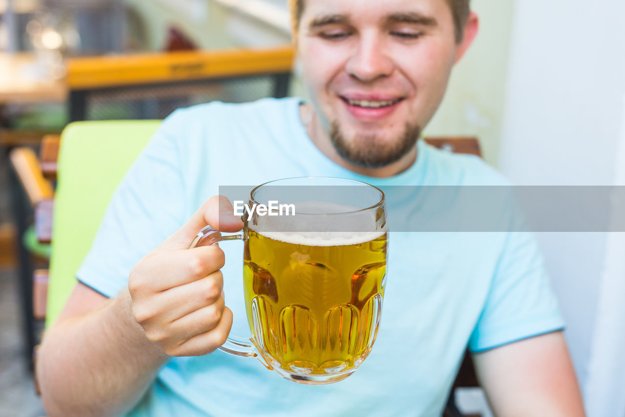 PORTRAIT OF SMILING MAN DRINKING GLASS