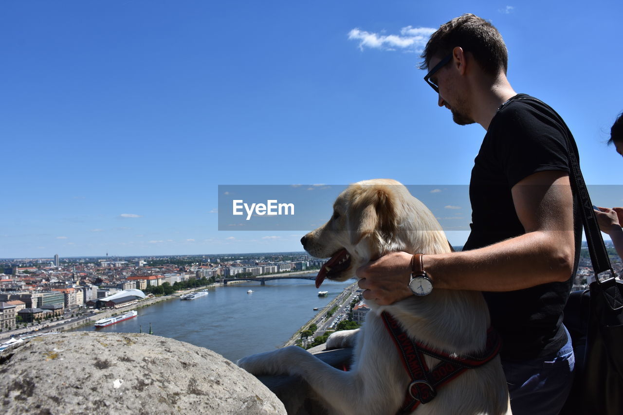 Side view of man with dog looking at lake from observation point