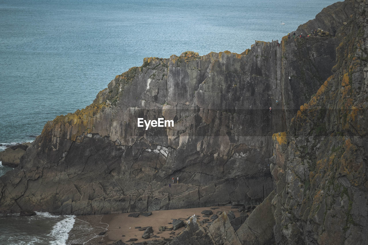 Rock formations on sea shore. rock climbers near sea.