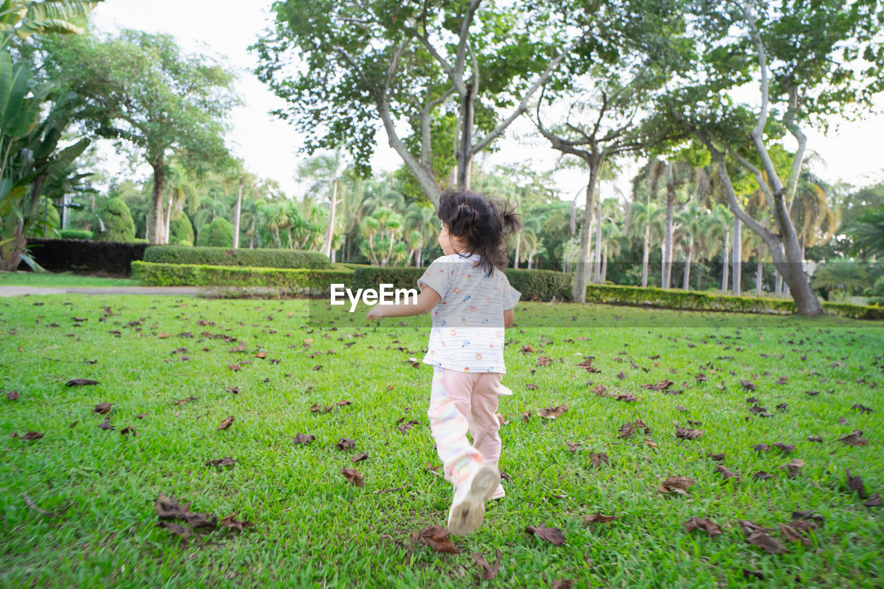 SIDE VIEW OF GIRL STANDING ON GRASS IN PARK