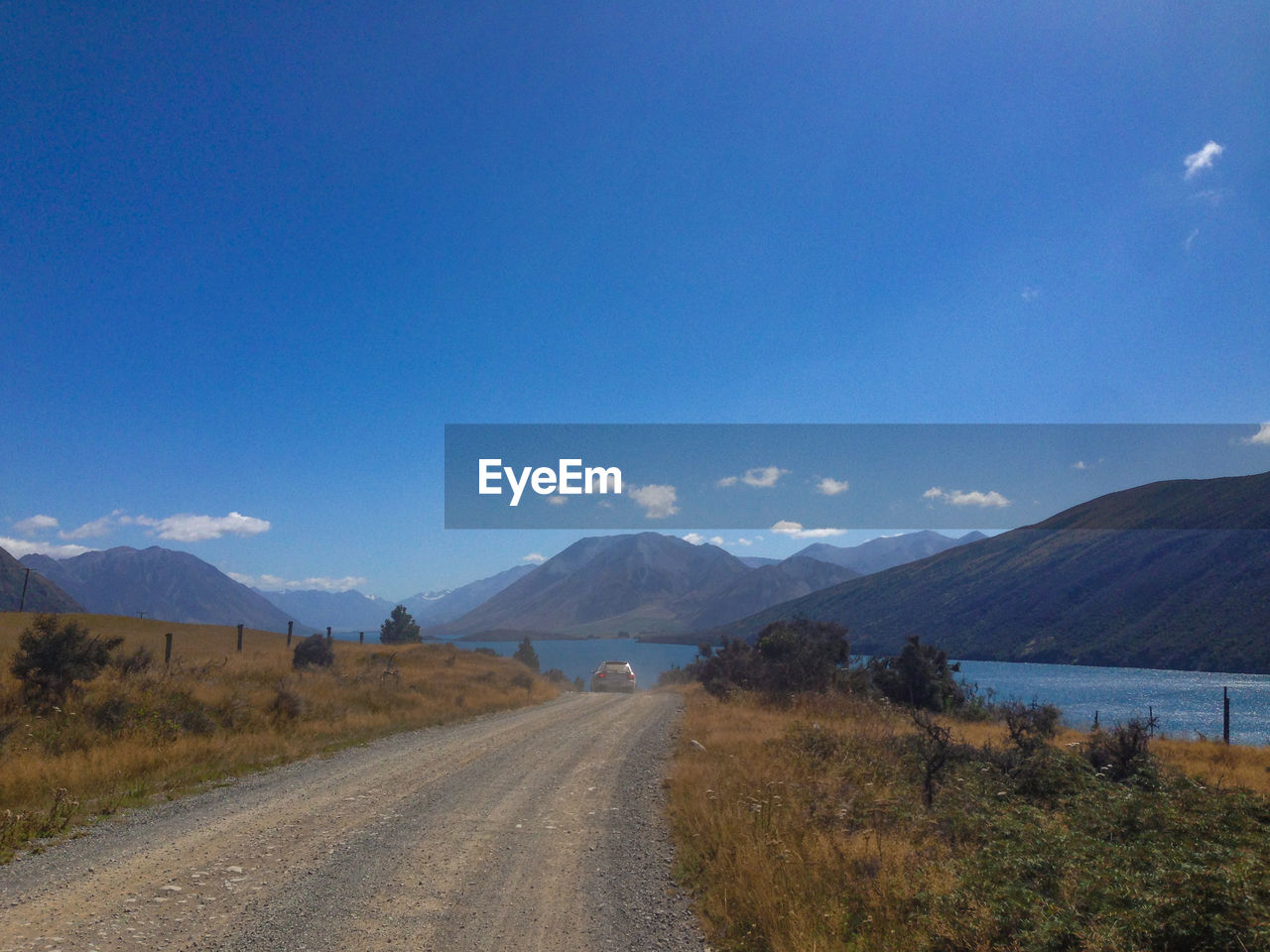 Road leading towards mountains against blue sky