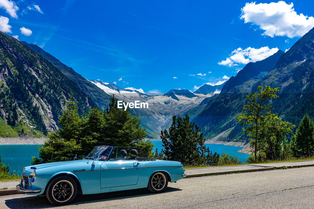 CAR ON ROAD AGAINST MOUNTAIN RANGE