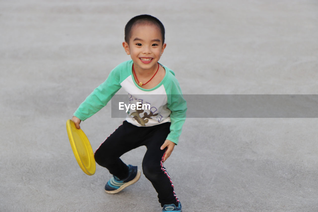 Cheerful boy playing with plastic disc at park