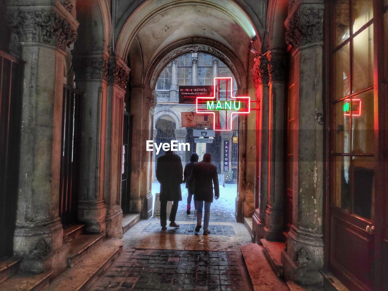 REAR VIEW OF PEOPLE WALKING ON ILLUMINATED BUILDINGS