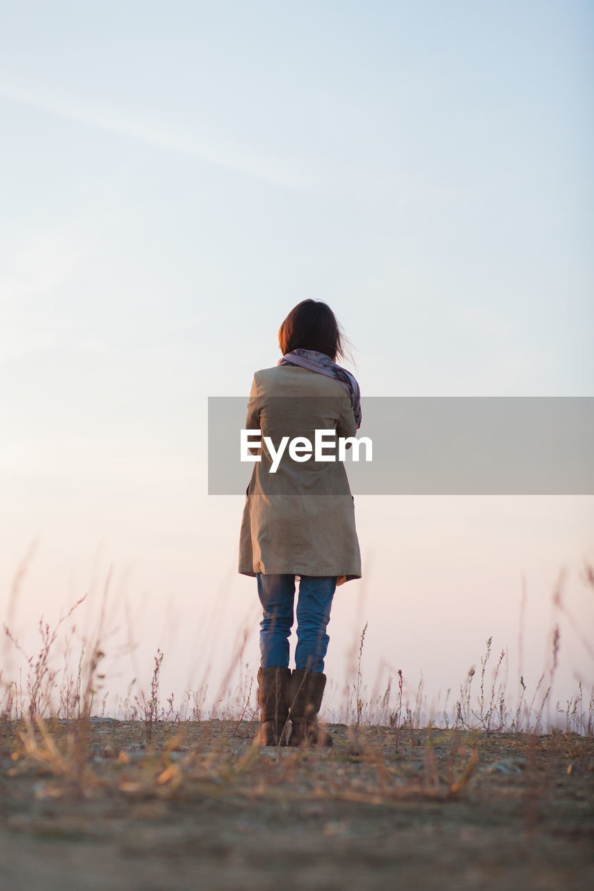 Rear view of woman standing on field against sky