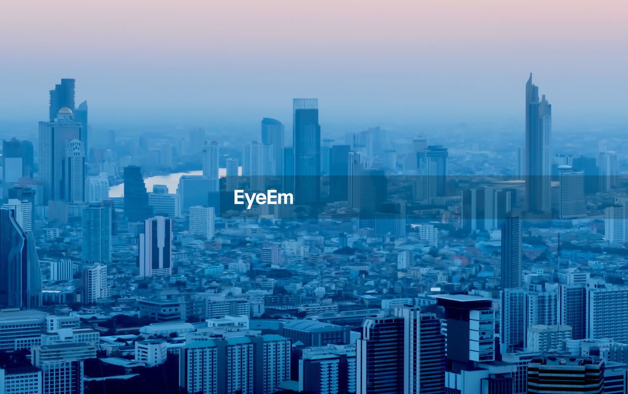 AERIAL VIEW OF BUILDINGS IN CITY AGAINST SKY DURING SUNSET