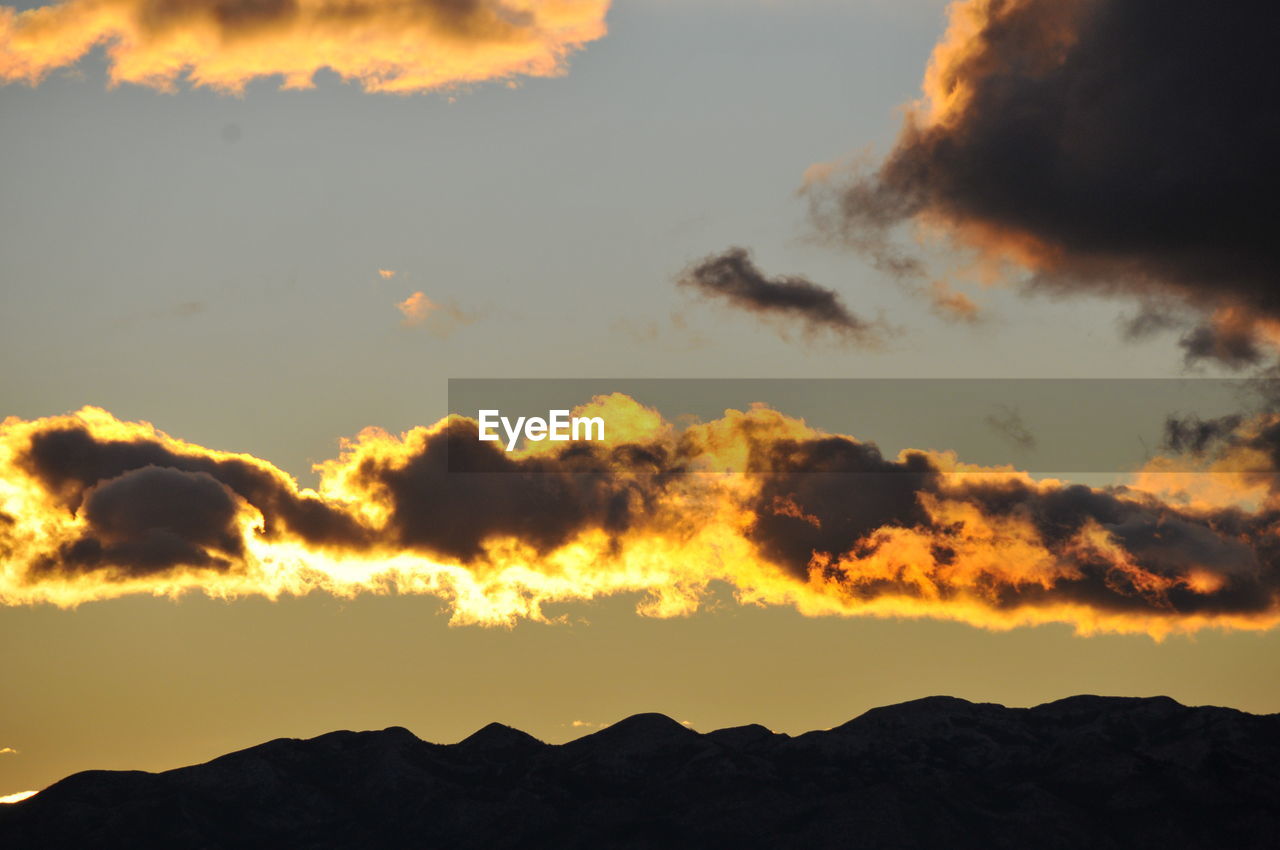 LOW ANGLE VIEW OF SILHOUETTE MOUNTAINS AGAINST ORANGE SKY