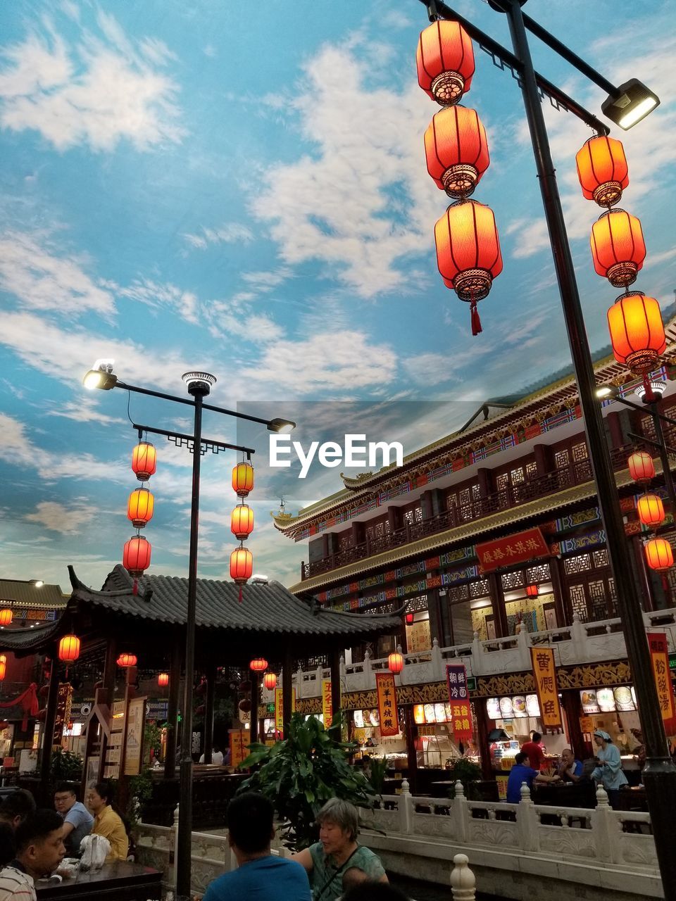 LOW ANGLE VIEW OF LANTERNS HANGING IN CITY AGAINST SKY