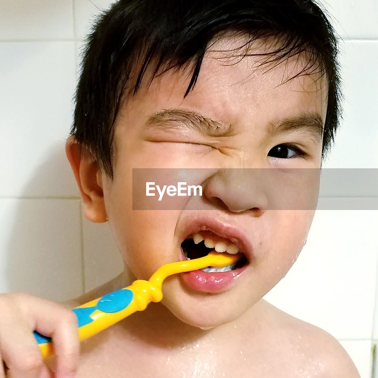 Close-up portrait of boy brushing teeth in bathroom