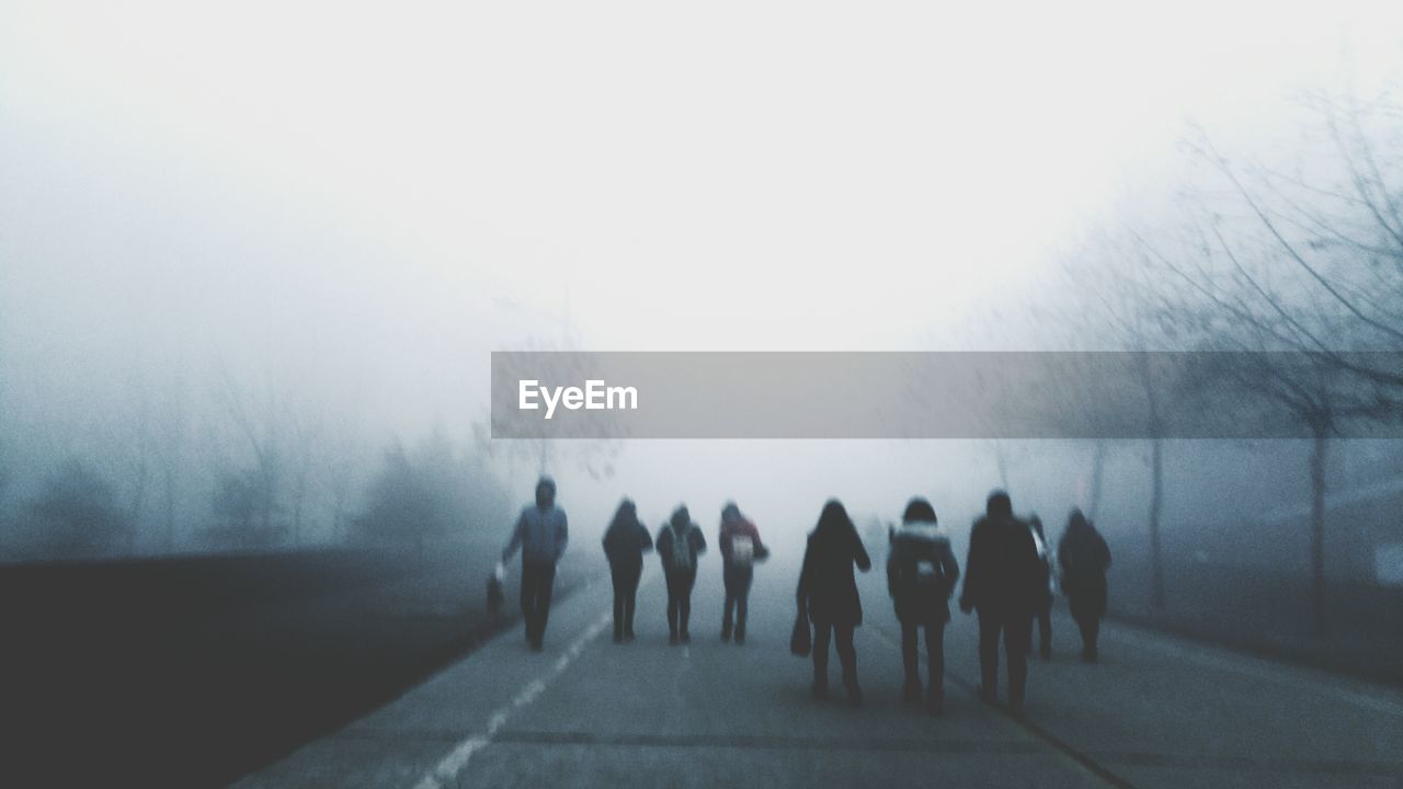 WOMAN STANDING IN FOGGY WEATHER