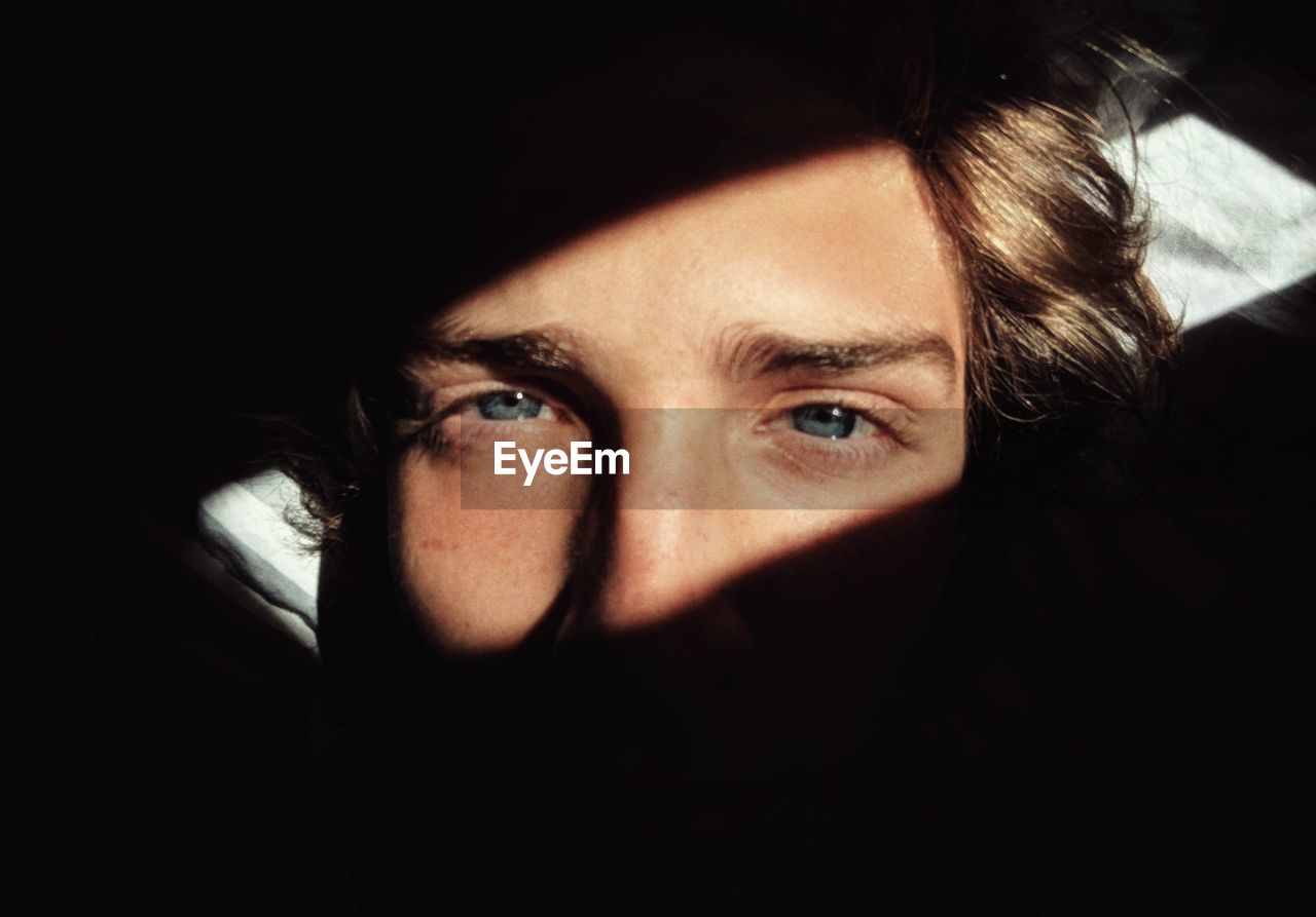 Close-up portrait of young man in darkroom