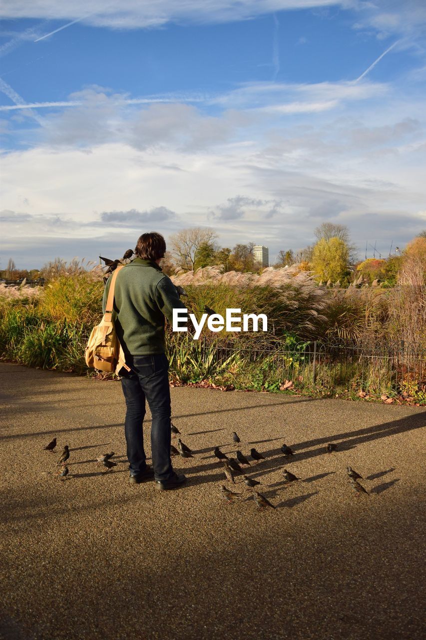 REAR VIEW OF MAN ON ROAD AGAINST SKY