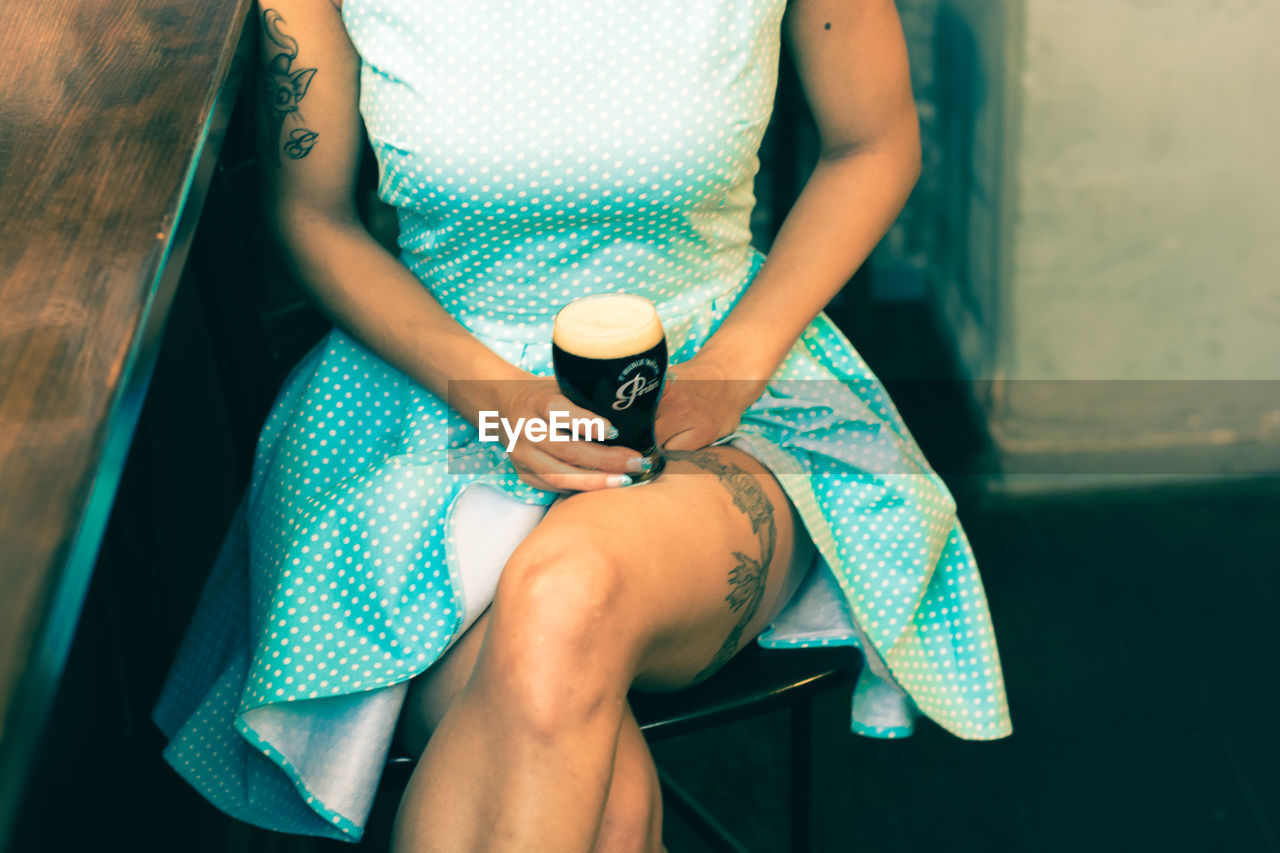 LOW SECTION OF WOMAN SITTING ON CHAIR