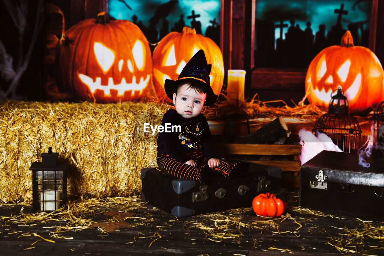 Cute boy sitting with jack o lantern during halloween