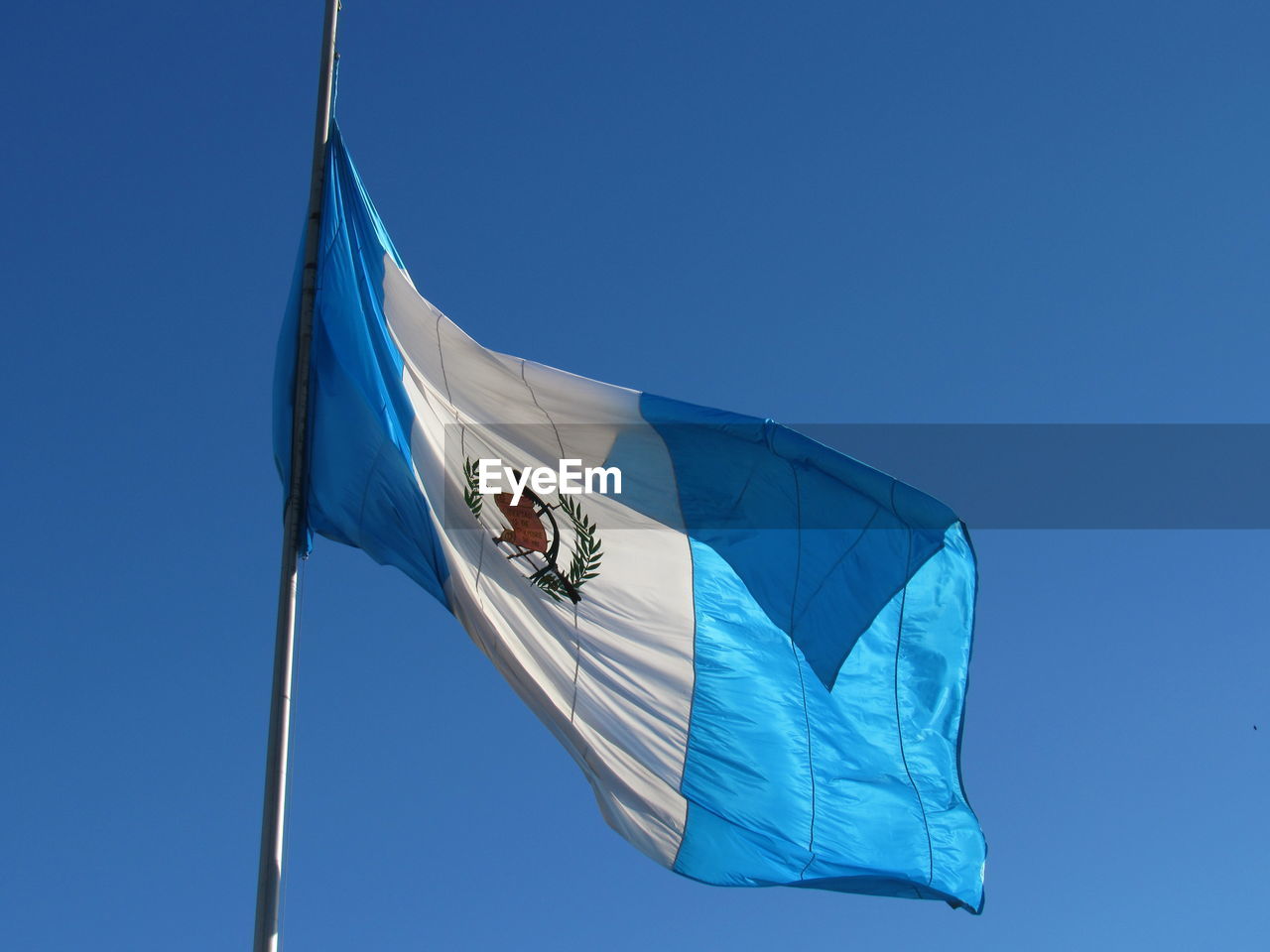 Low angle view of flag against clear blue sky