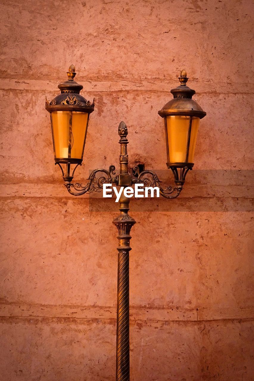 ILLUMINATED STREET LIGHT ON WALL OF BUILDING WITH OLD LAMP