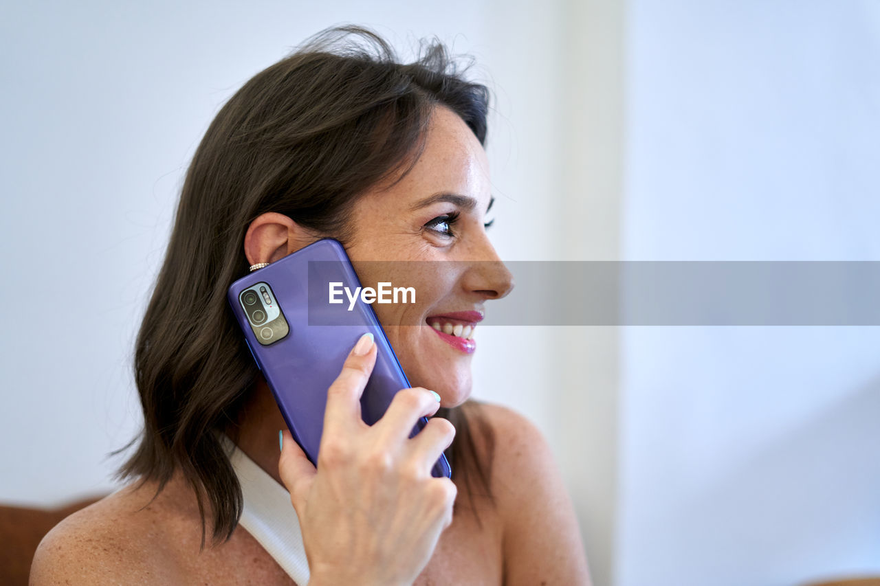 Positive female entrepreneur talking mobile phone at table in cafe