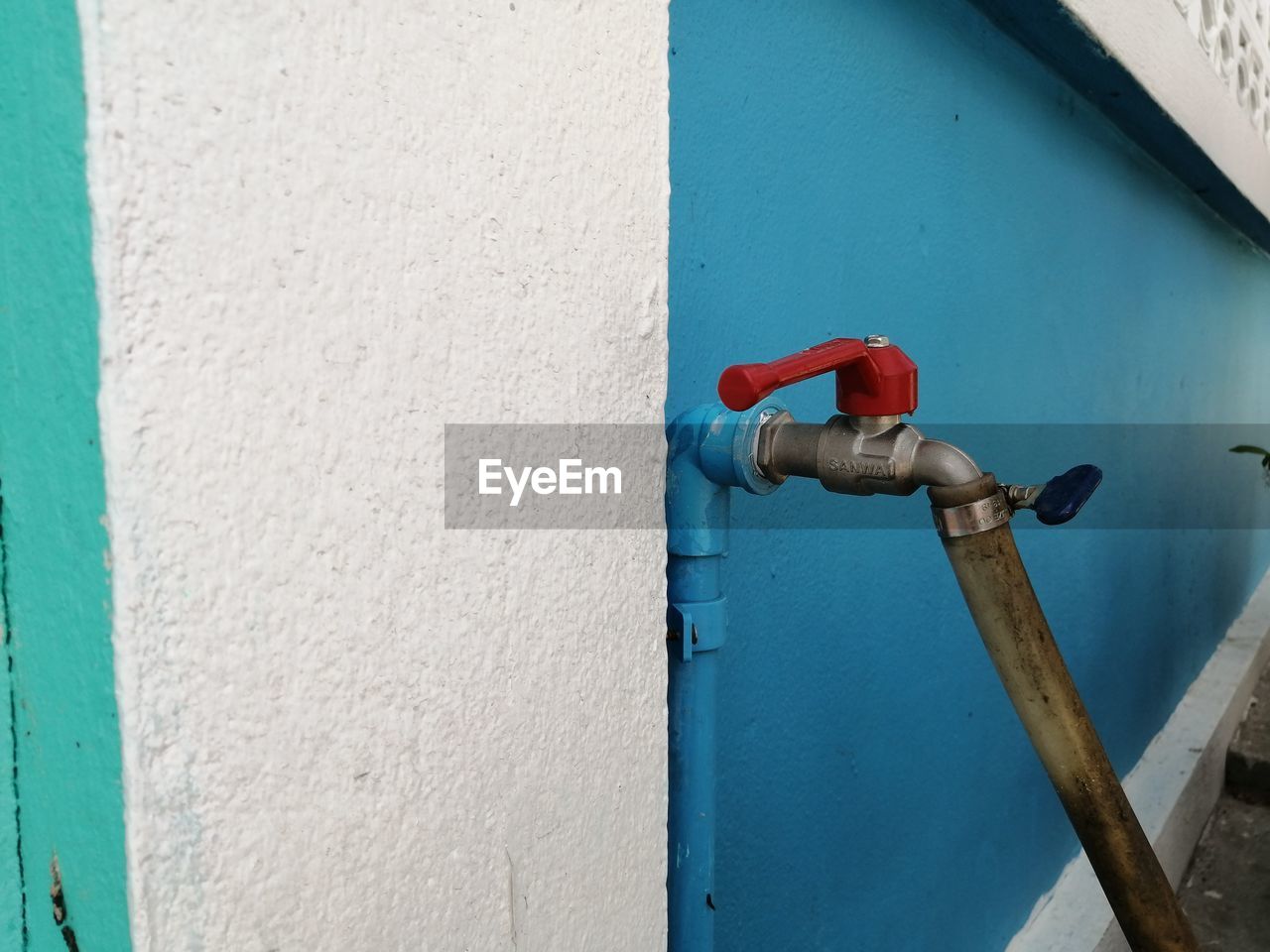 CLOSE-UP OF BLUE PIPE AGAINST WALL