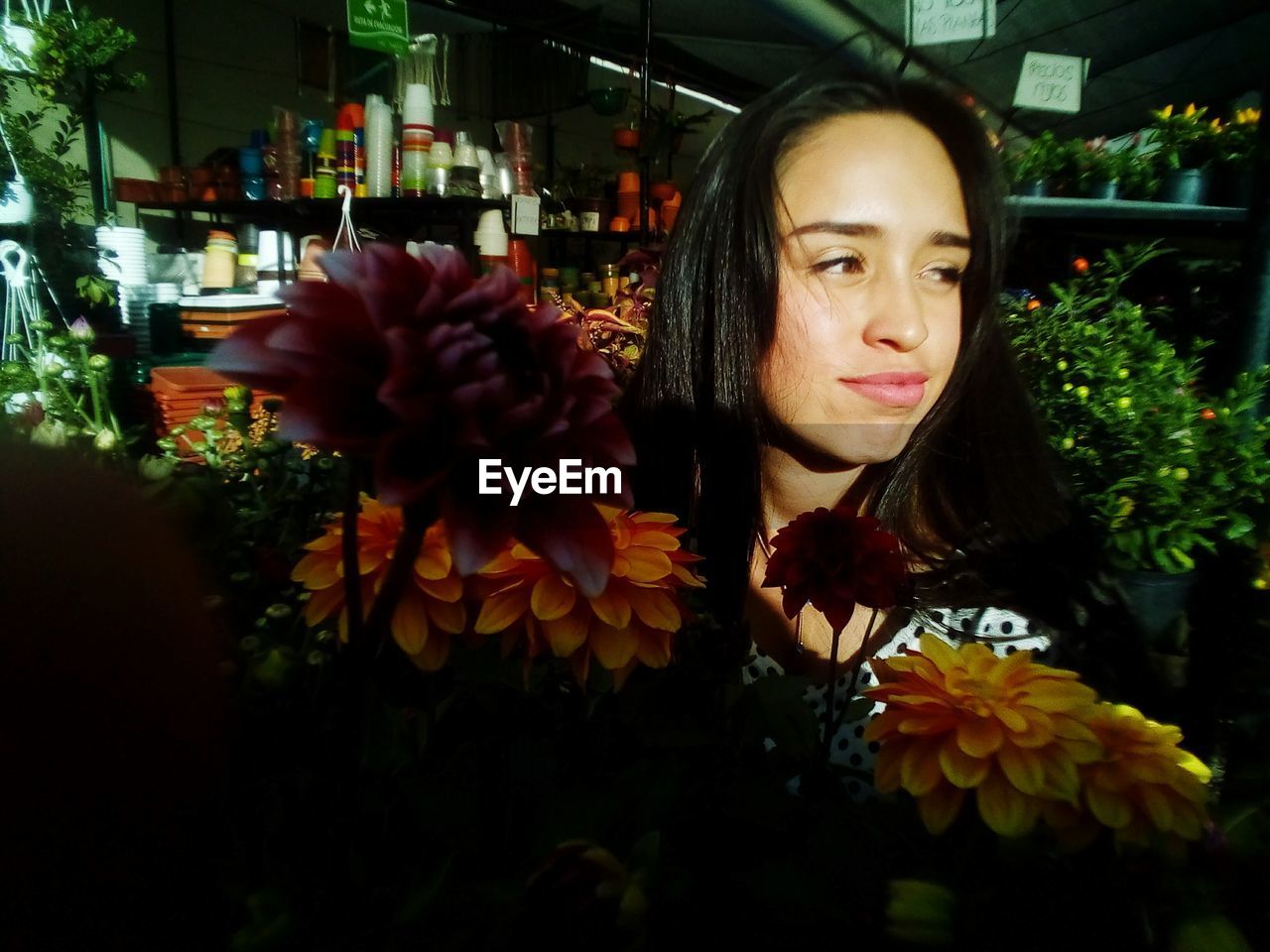 BEAUTIFUL YOUNG WOMAN WITH FLOWER BOUQUET AGAINST BLURRED BACKGROUND