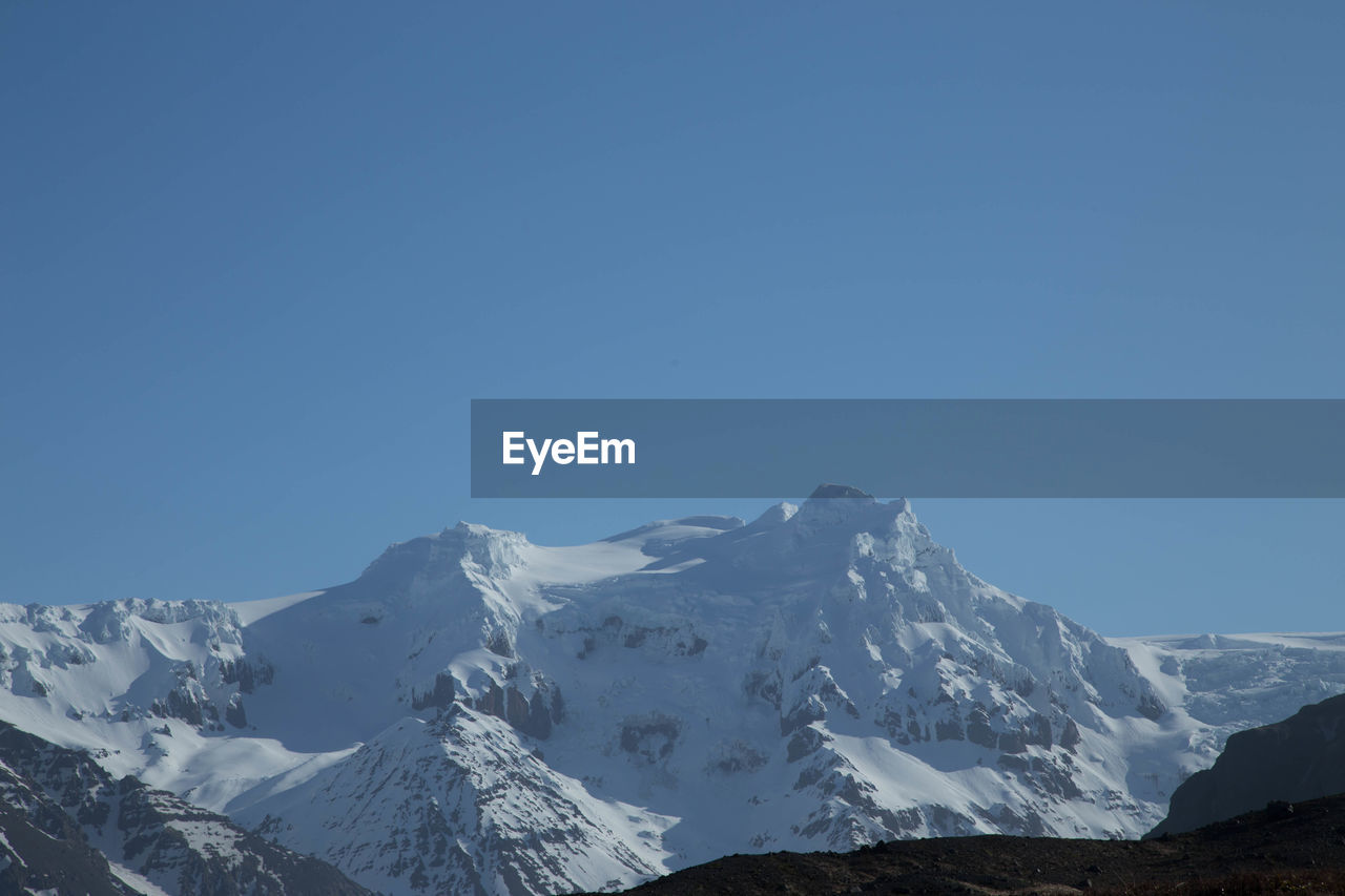 Scenic view of snowcapped mountains against clear blue sky