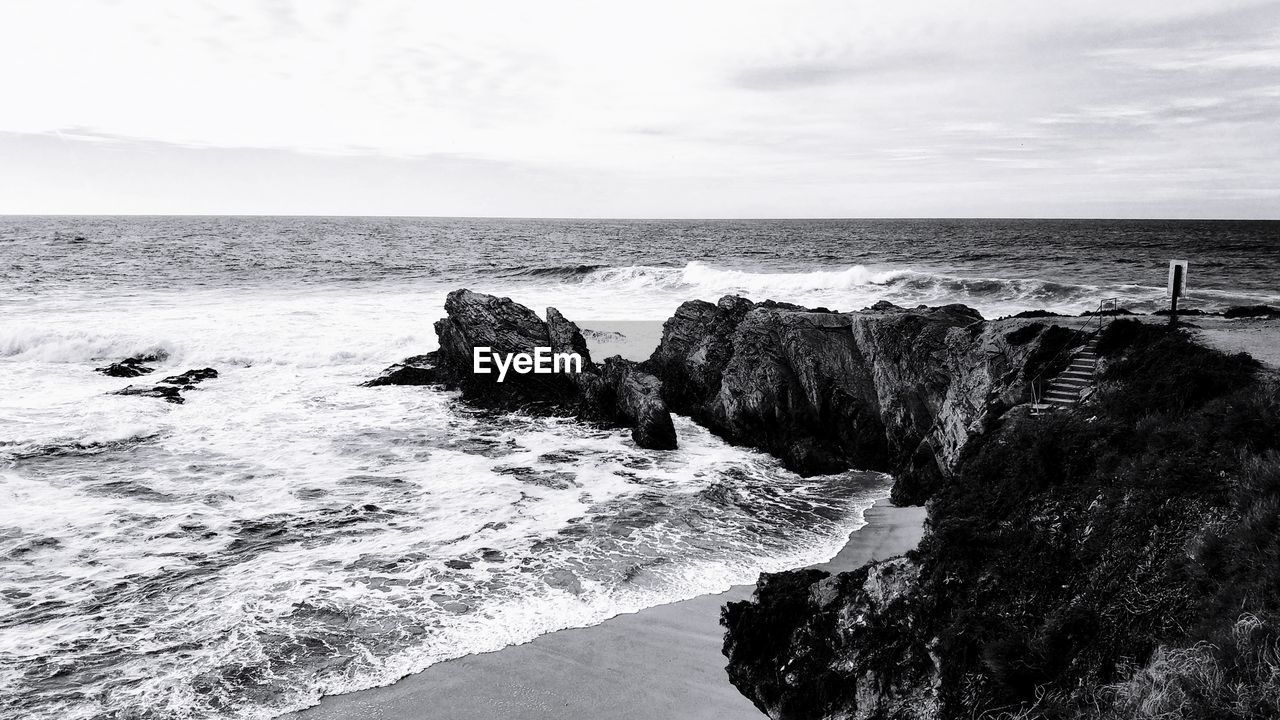 ROCKS ON BEACH AGAINST SKY