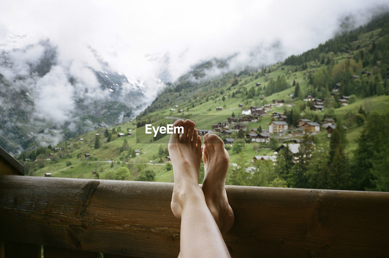 Low section of woman relaxing in balcony against mountains